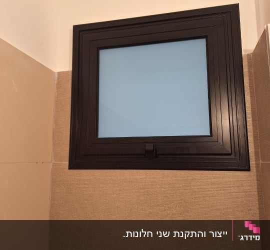 חלון אלומיניום עם מסגרת כהה על קיר